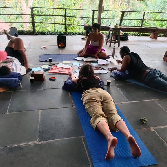 Participants doing yoga or stretching exercises on mats in an open-air pavilion