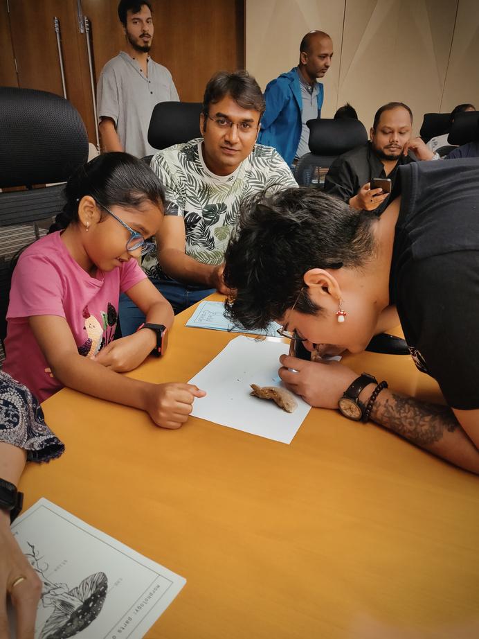 Group gathered around a table examining documents with a fungal specimen